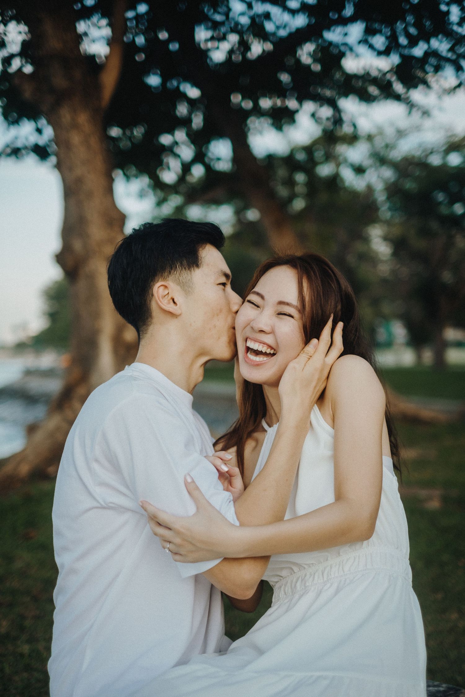 Candid sequence of loving couple sharing intimate laughter and affection in park setting with trees.