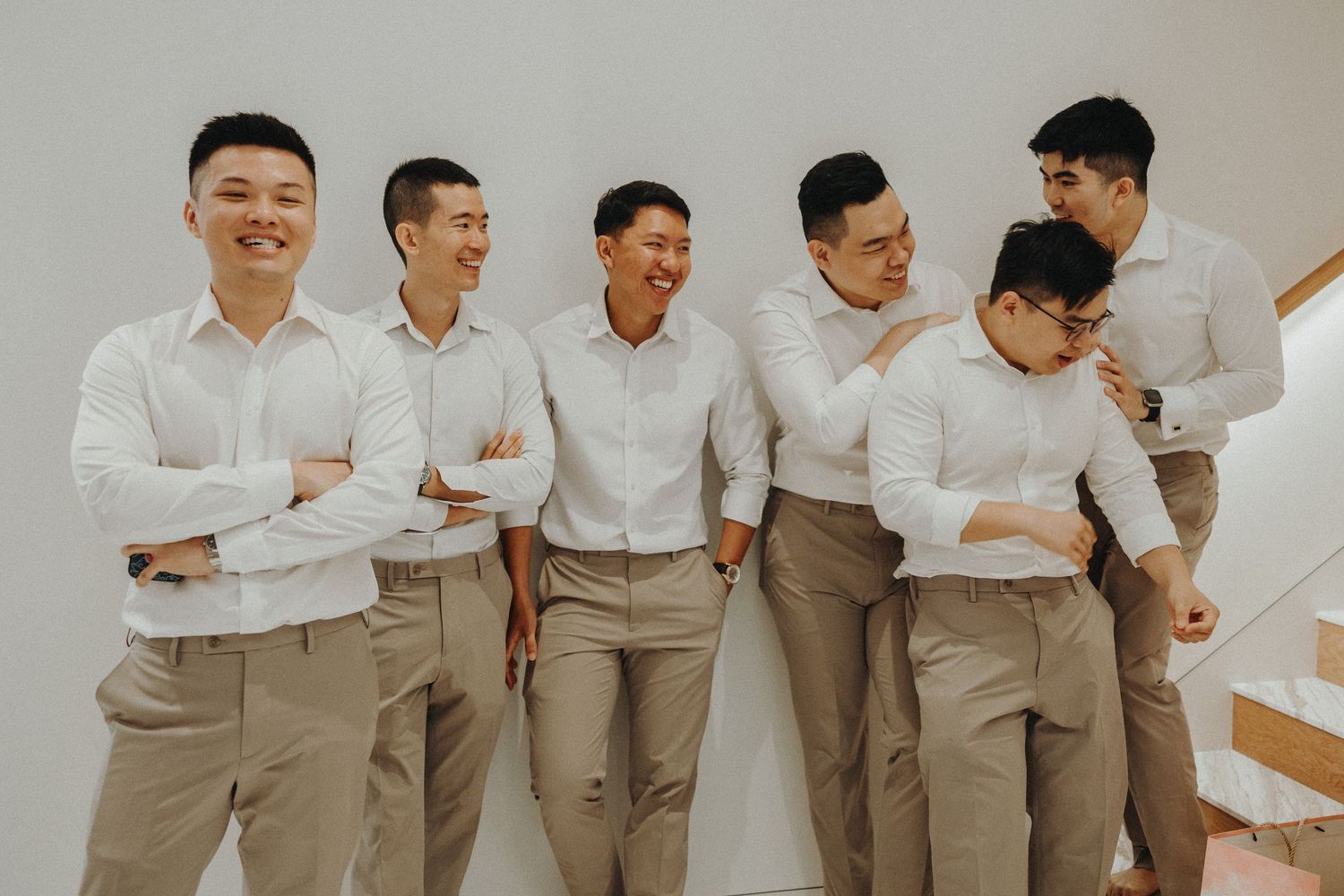 Groomsmen in matching white shirts and khaki pants posing together in a line.
