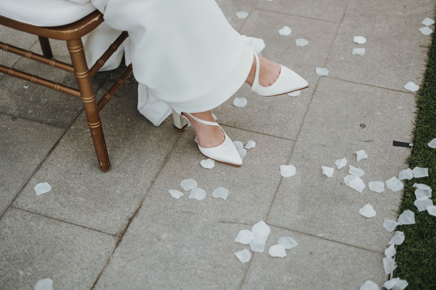 White rose petals scattered on concrete ground creating a romantic wedding ceremony path.