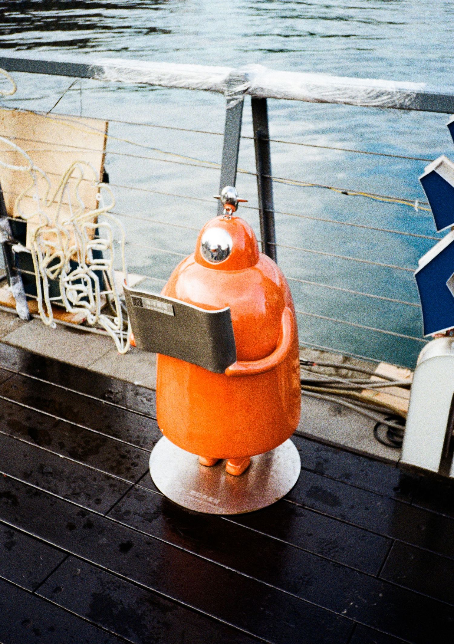 Orange and white kettles on dark wooden deck with water visible in background.