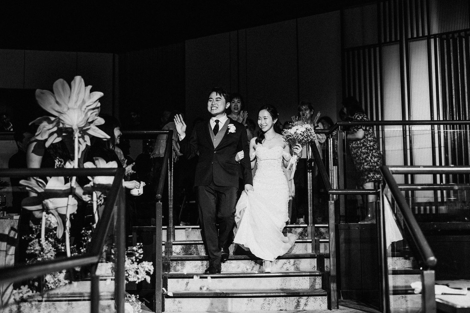 A black and white photo of a couple descending church stairs after their wedding ceremony.