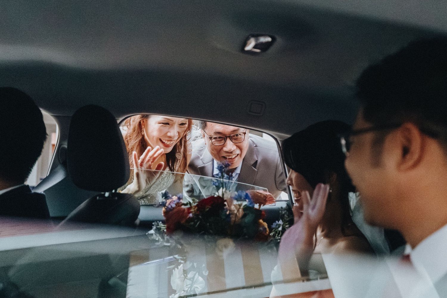 People share laughter and conversations while seated in a car during a wedding celebration.