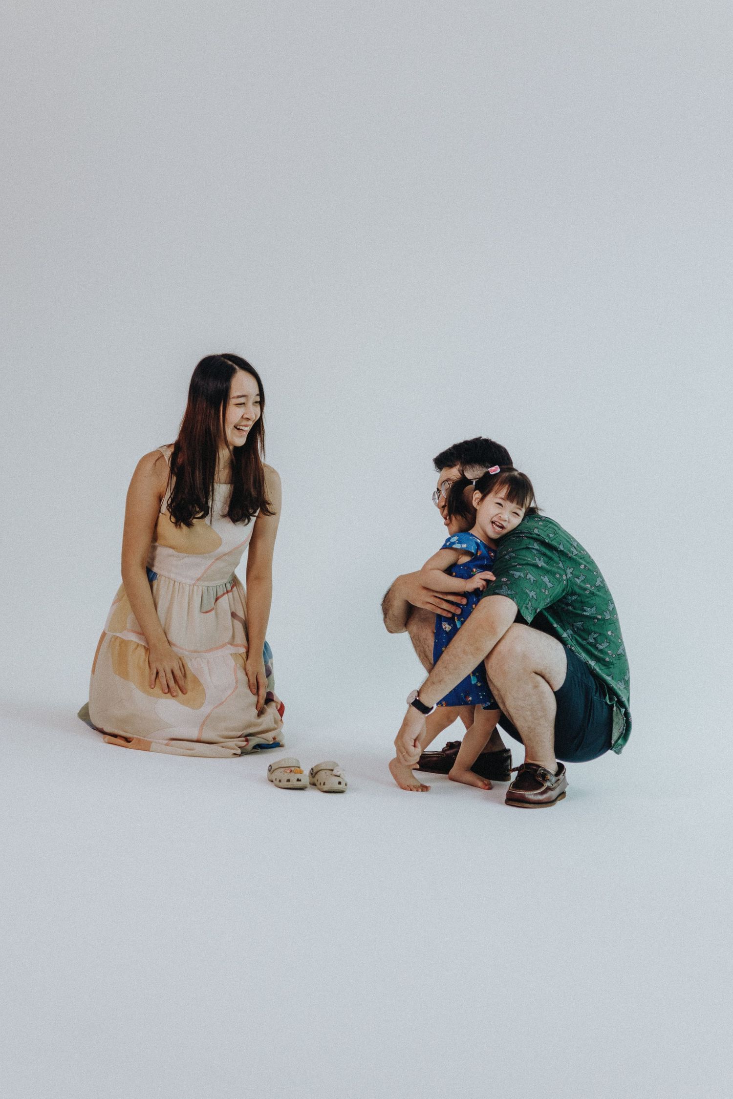 Two people sitting on the floor examining items together in a minimalist setting.
