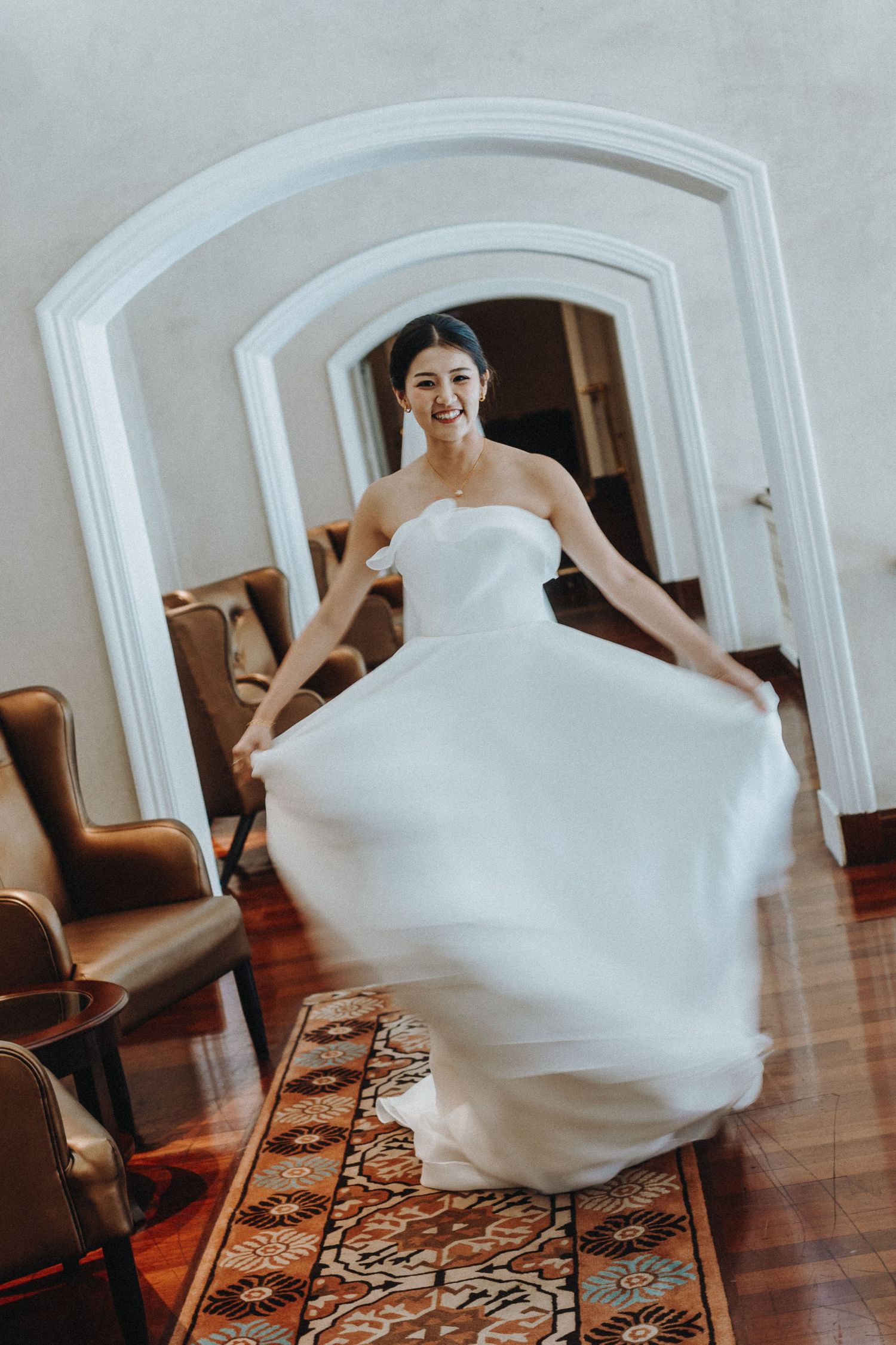 A portrait of someone in a flowing white wedding dress twirling in an elegant room with arched doorways.