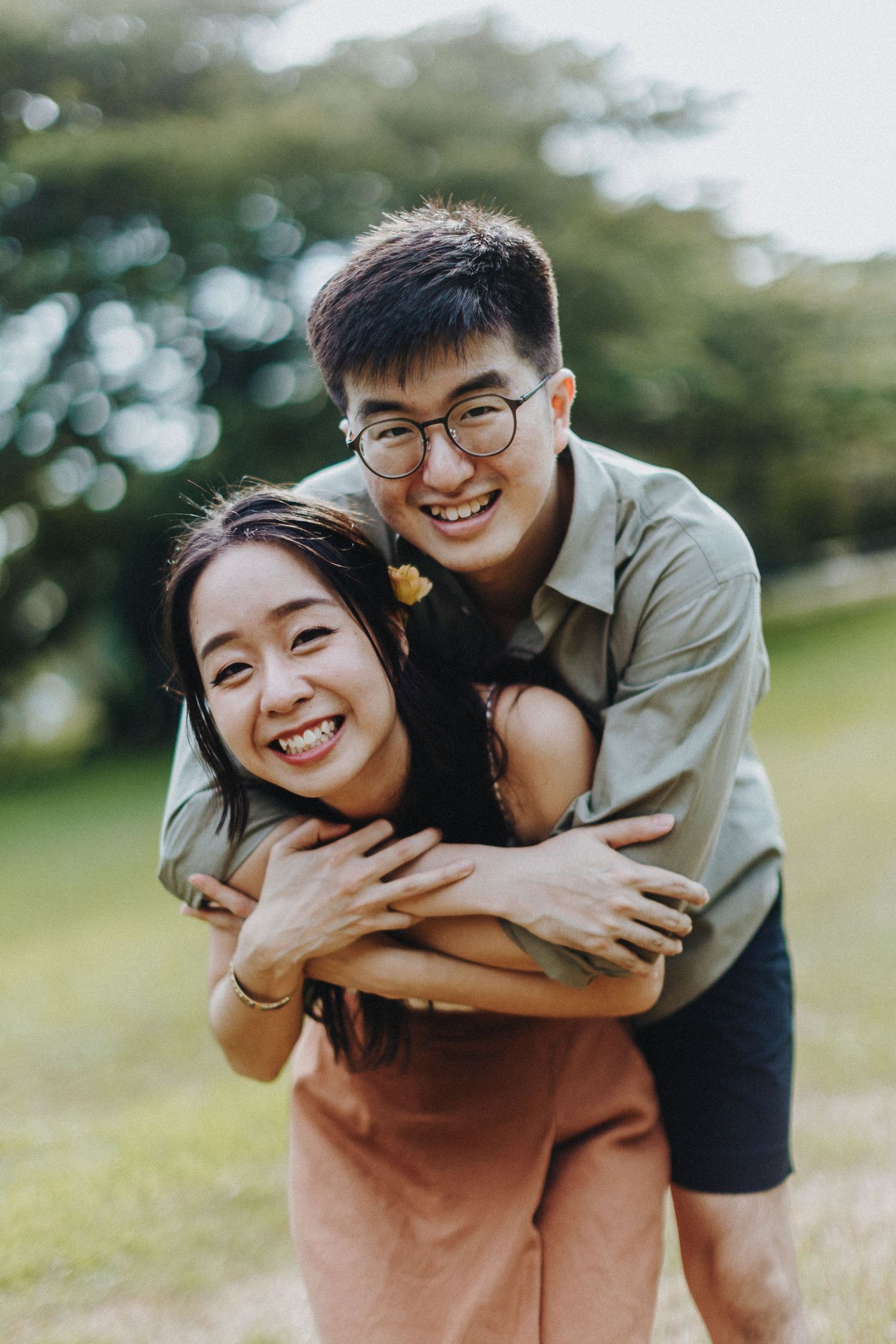 A loving couple shares playful moments and embraces while spending time together in a sunny outdoor park setting.