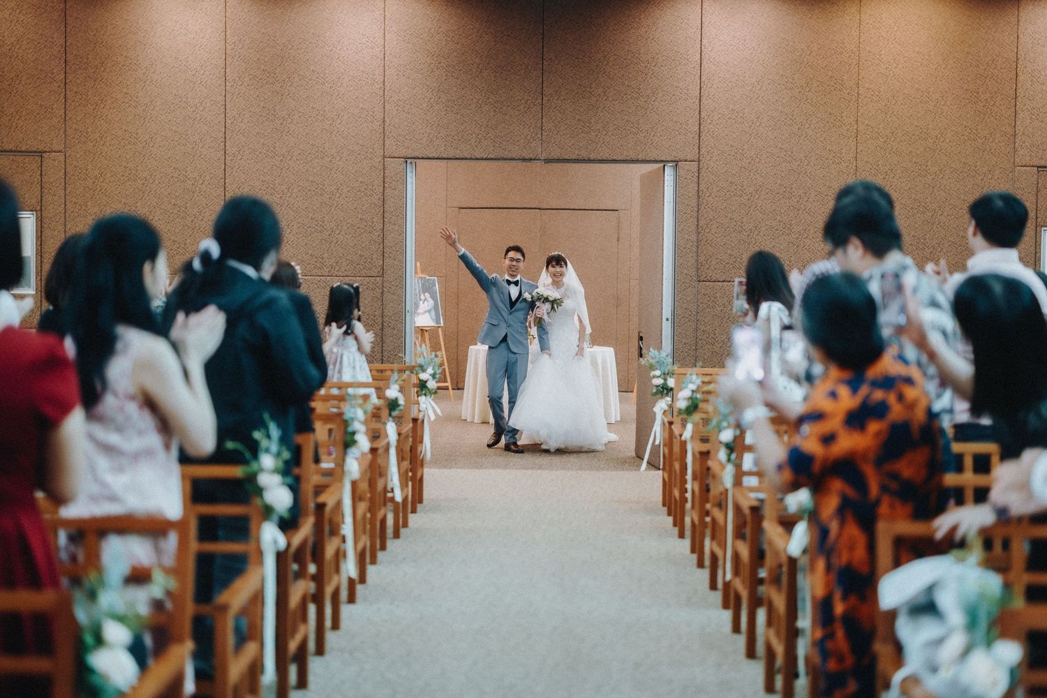 Wedding ceremony in progress with guests seated in rows of wooden chairs as couple celebrates at the altar.