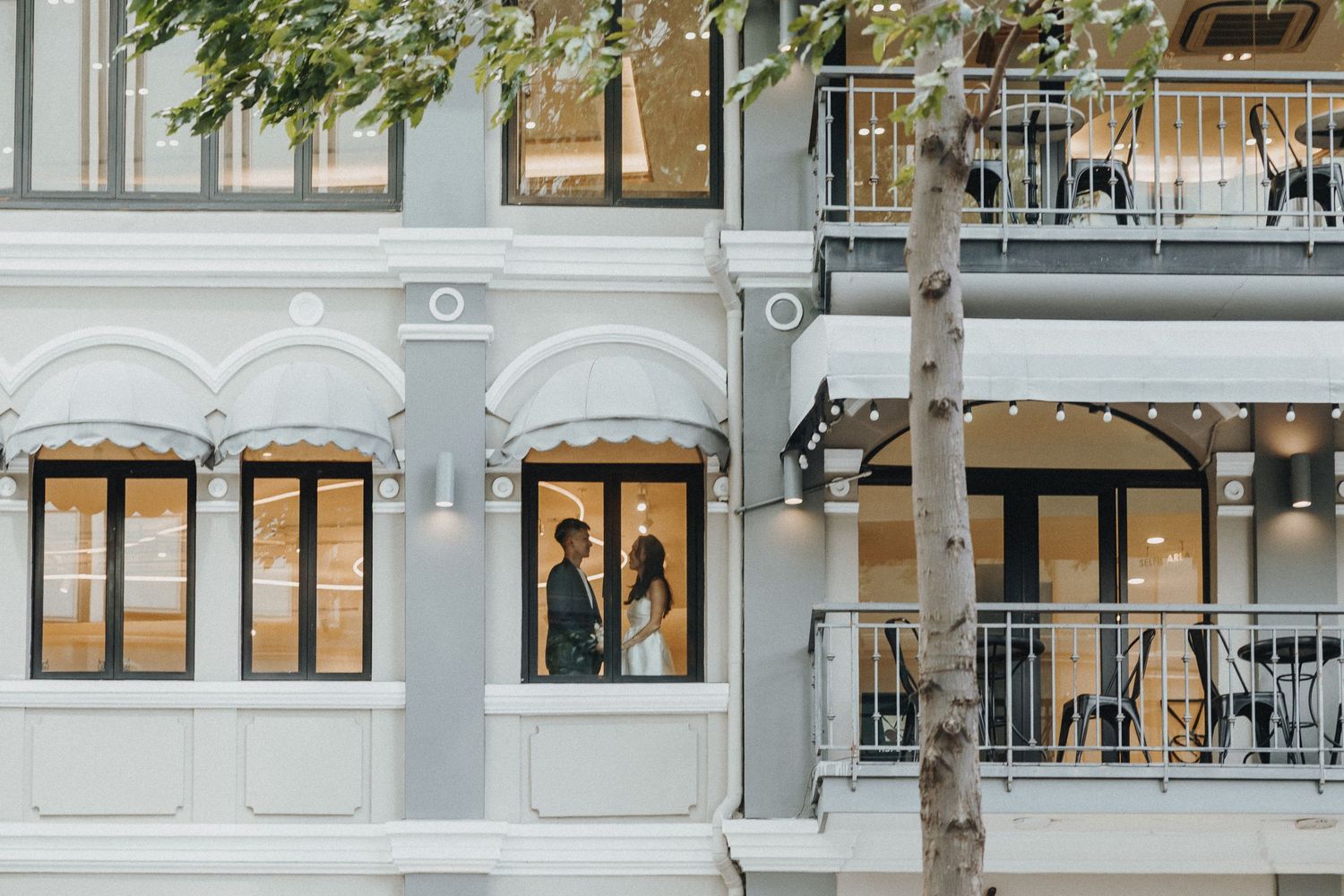 Elegant grey building exterior with arched windows and ornate architectural details featuring wrought iron balconies.
