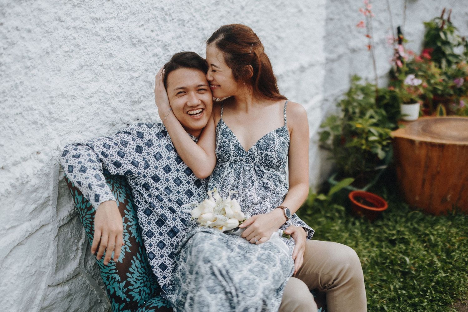 Intimate engagement portrait showing tender moment between couple against garden wall.