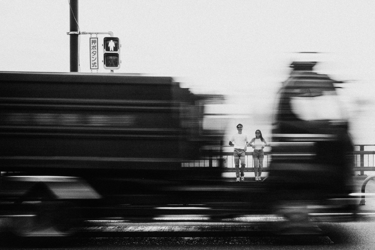 Black and white motion blur photograph of a train passing through a station platform.