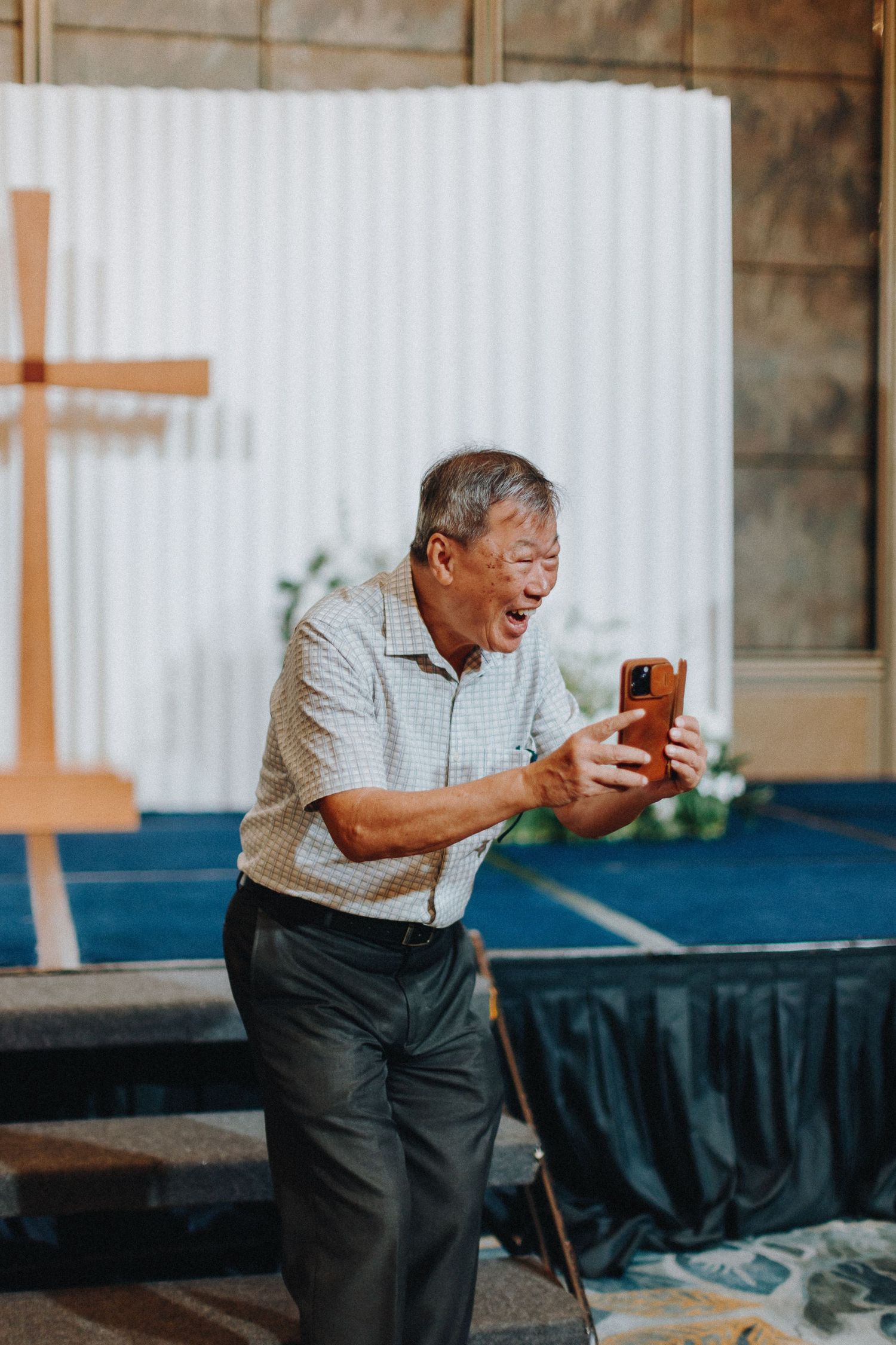 An elderly guest laughing joyfully during wedding reception celebrations.