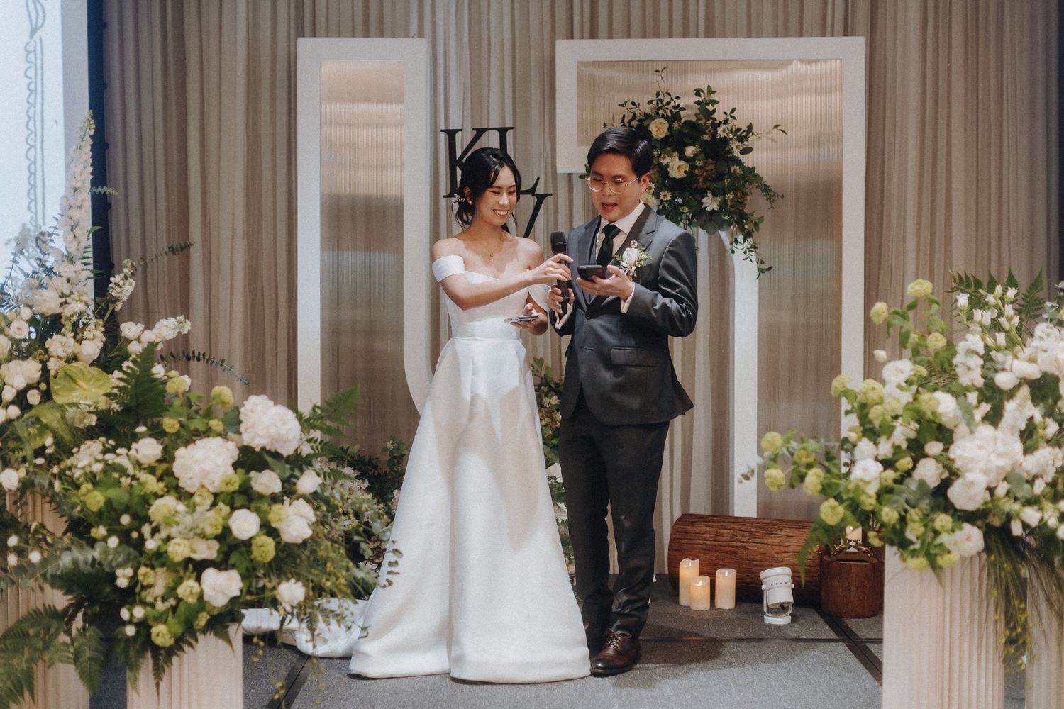 An elegant wedding ceremony setup with white floral arrangements and natural lighting through glass windows.