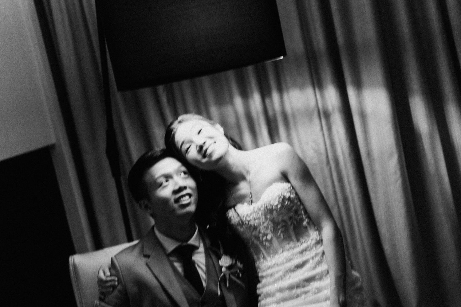 An artistic black and white photo captures a couple in wedding attire in dramatic lighting.