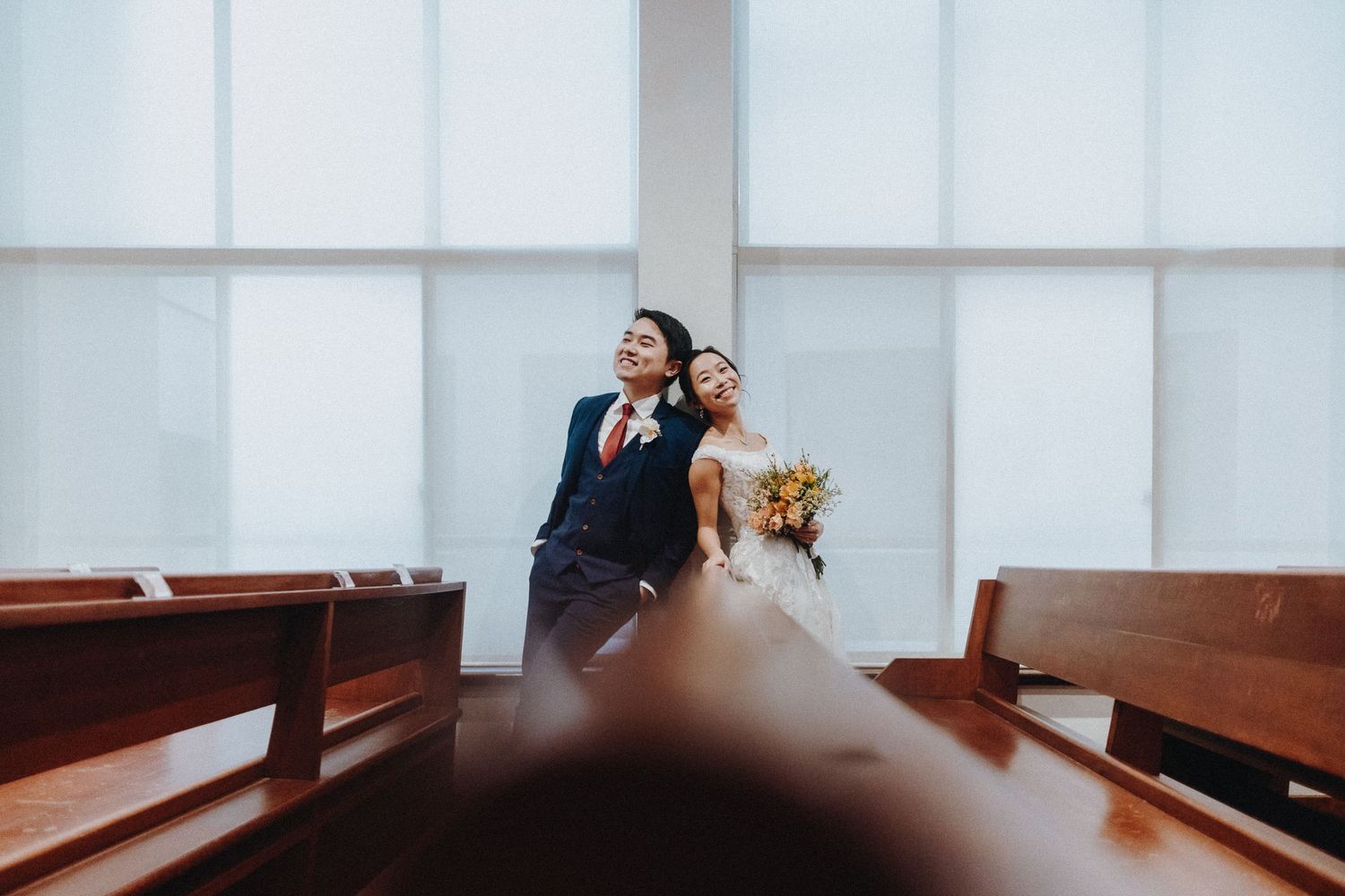 Wedding party poses playfully in front of white modern church interior.