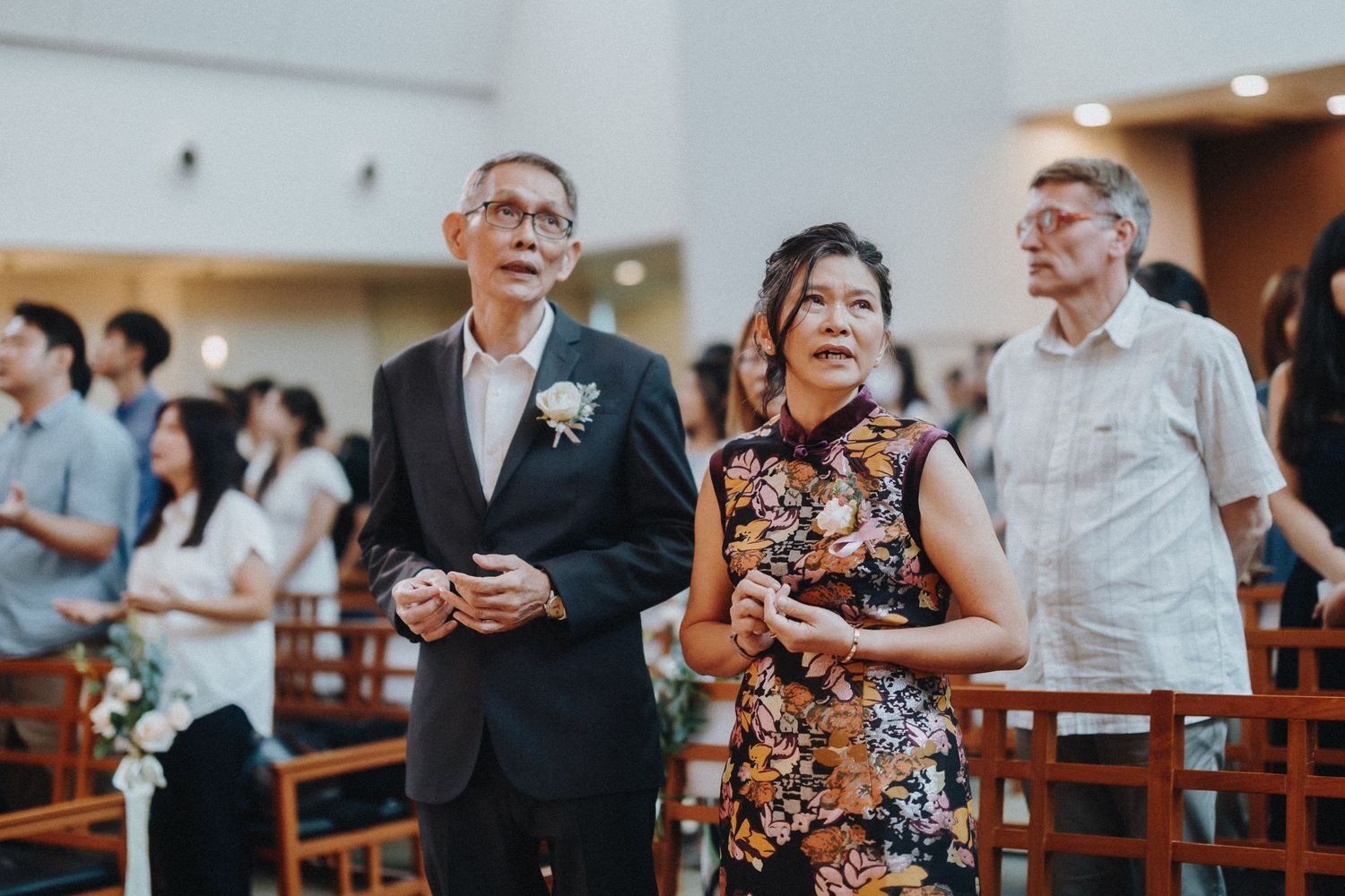 Wedding guests standing in church pews during a ceremony.