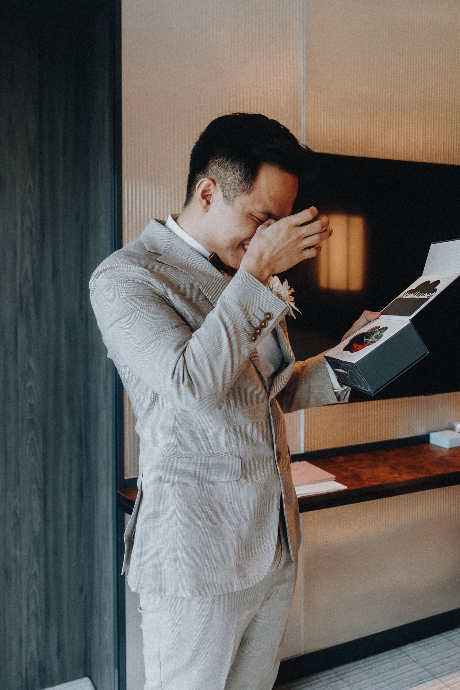 Emotional groom reading letter while standing in modern interior.