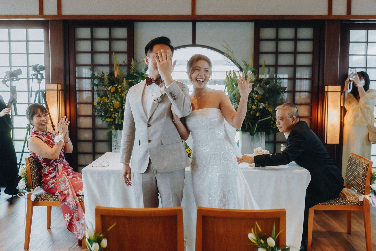 Wedding party gathering together for celebration photos at a Japanese-style venue with wooden architecture.