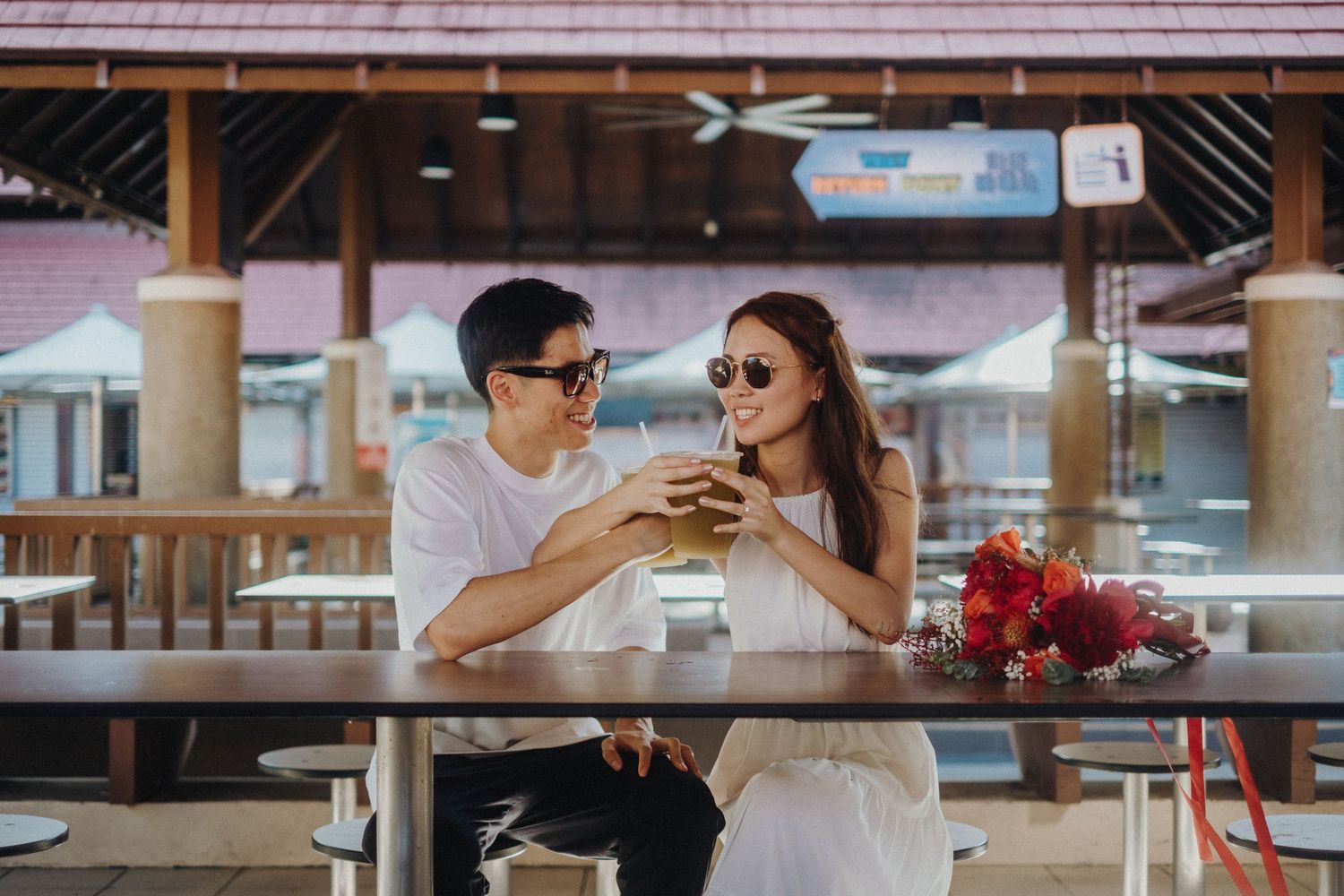 A couple shares drinks at an outdoor cafe table with floral decorations.