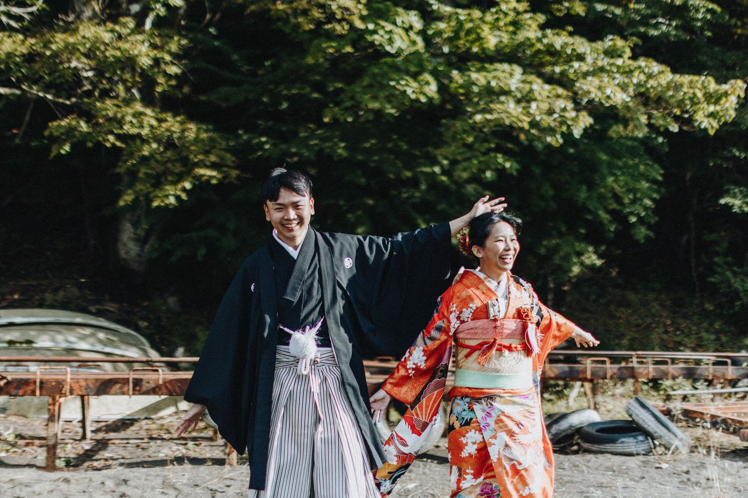 Couple in traditional kimono and hakama walking together through a serene garden path.