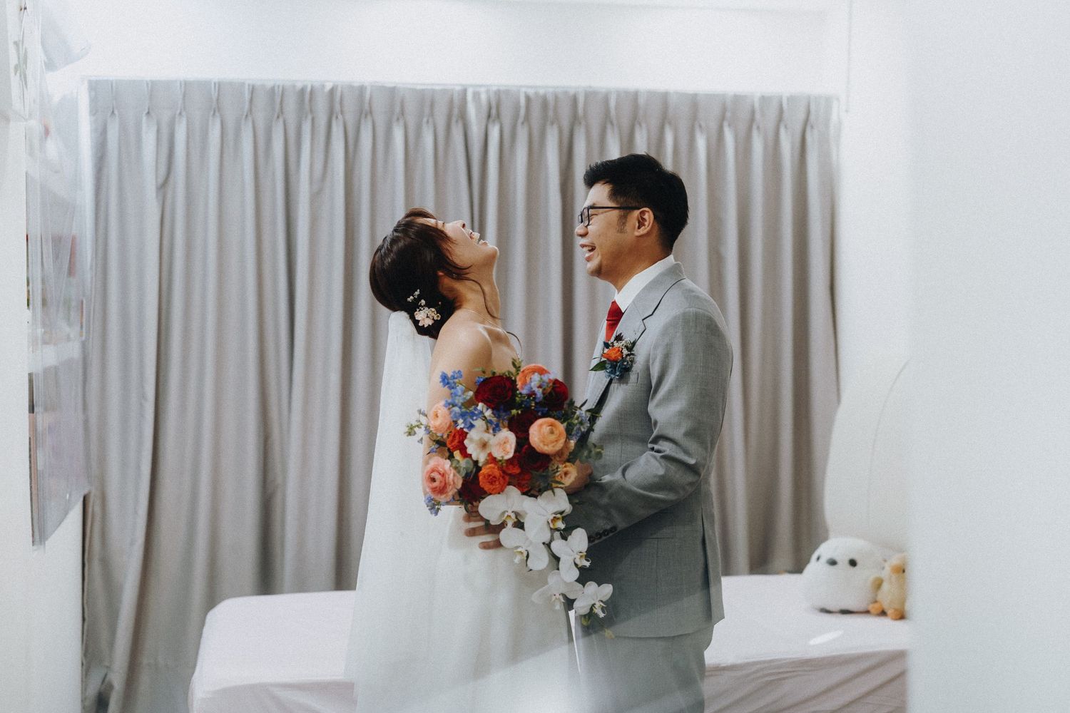 A couple in wedding attire shares an intimate moment together while holding a vibrant bouquet of flowers.
