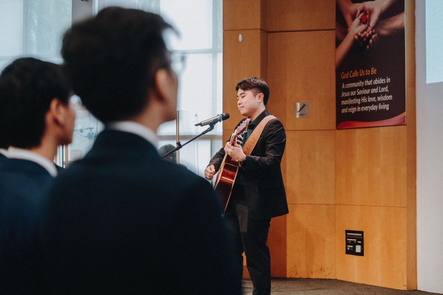 A musician performs with an acoustic guitar during a wedding ceremony in an indoor venue.