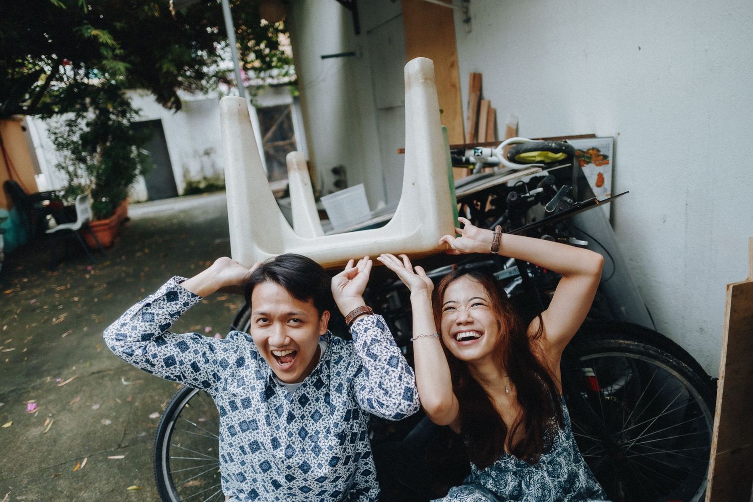 Joyful outdoor engagement photoshoot showing playful couple with arms raised.
