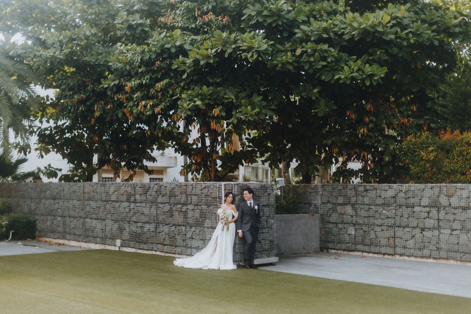 A romantic outdoor wedding ceremony set against a stone wall and lush greenery.