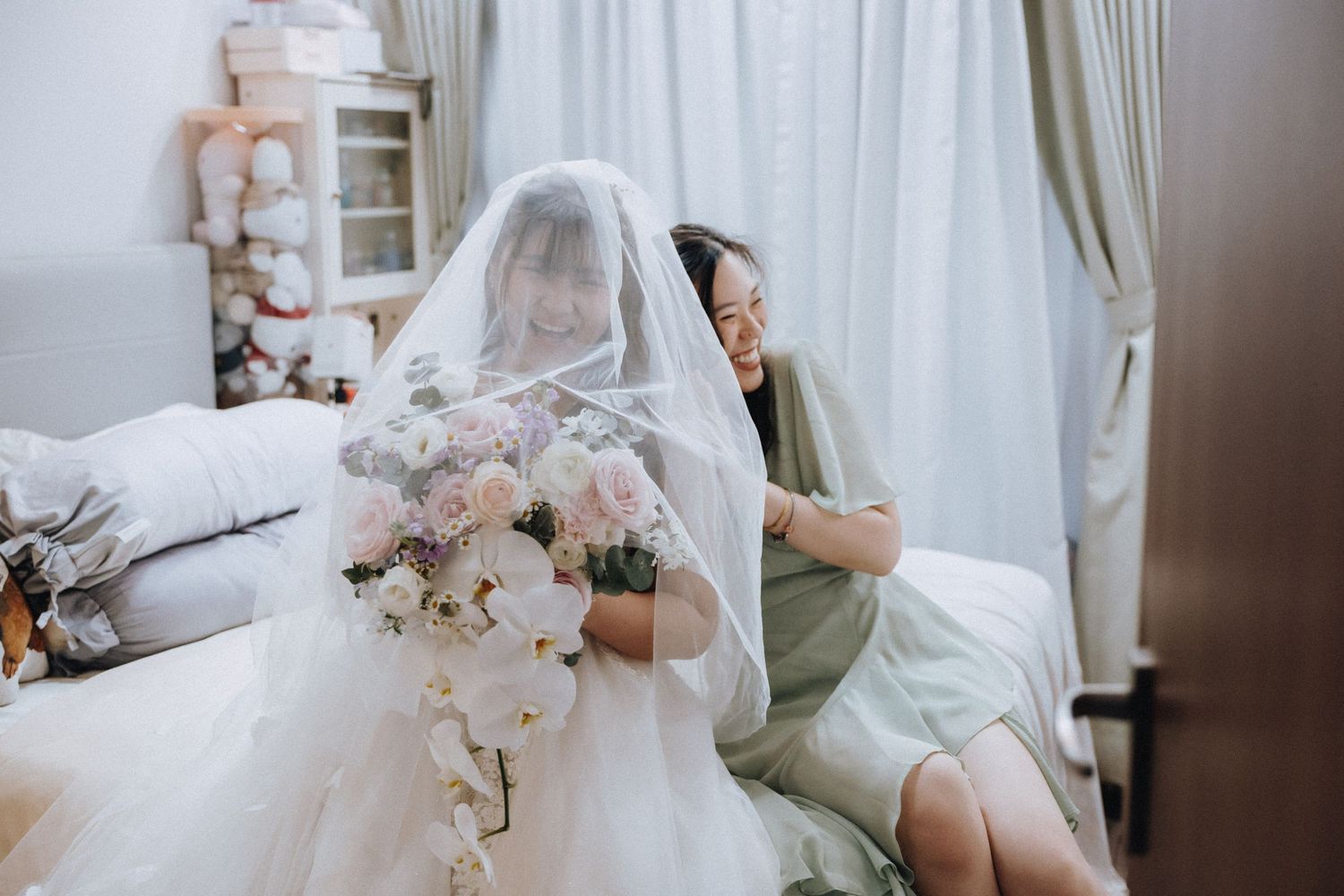 Bride in white wedding dress holds elegant white orchid bouquet while getting ready in bridal suite.