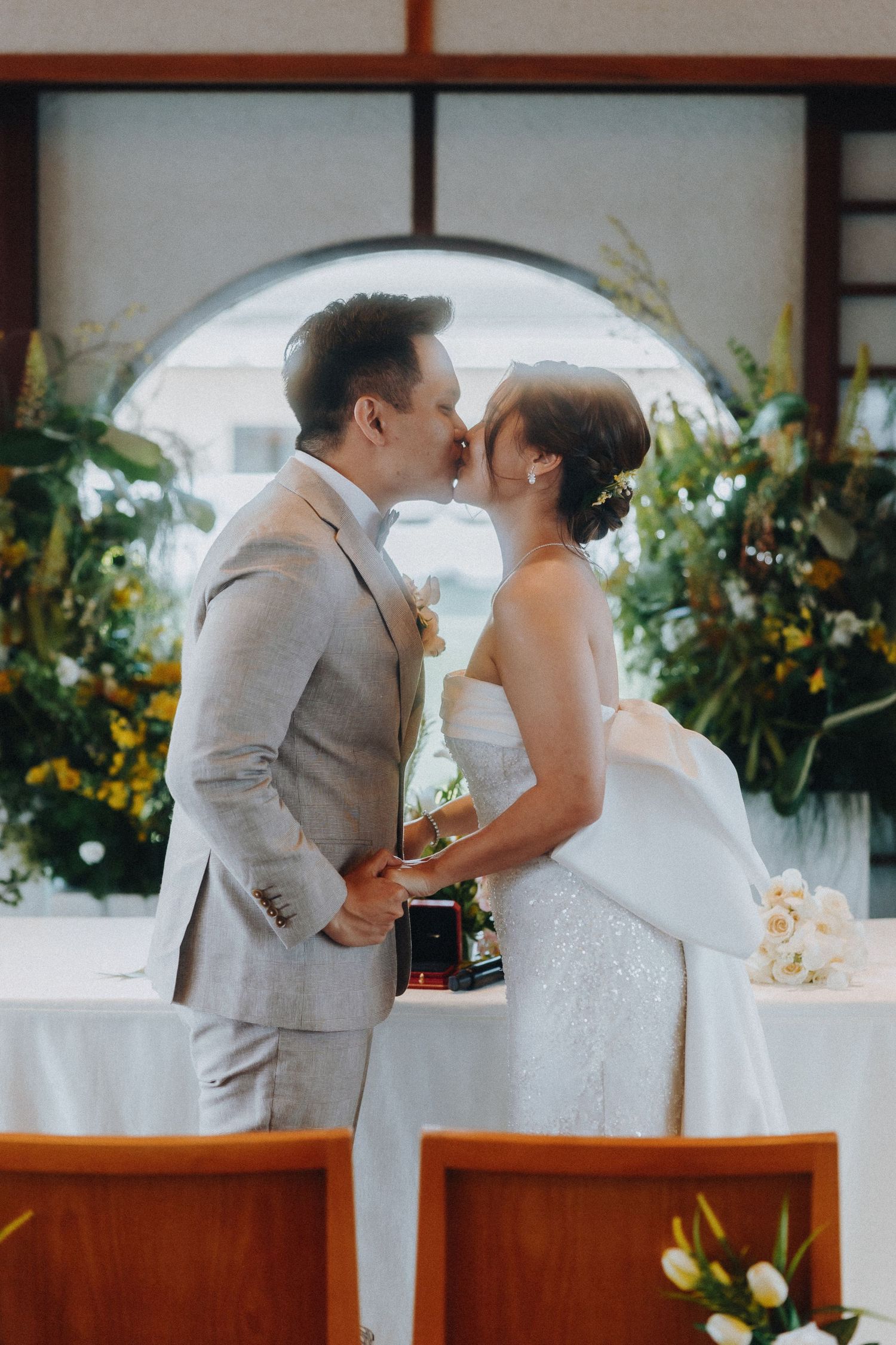 Romantic moment during wedding ceremony with floral decorations in Japanese-style interior.