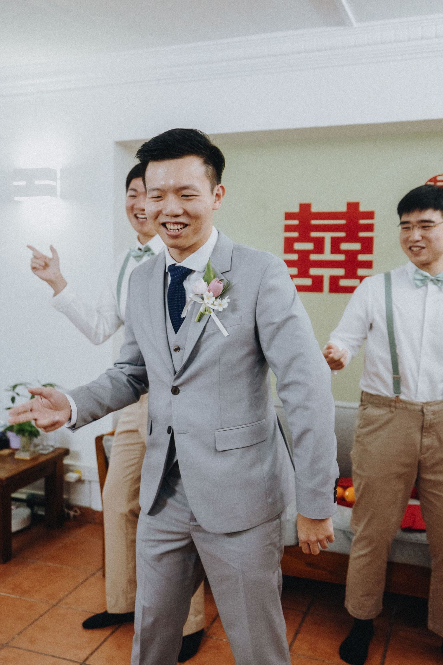 Wedding celebration in a room with traditional Chinese double happiness symbol showing joyful moments in grey suits.