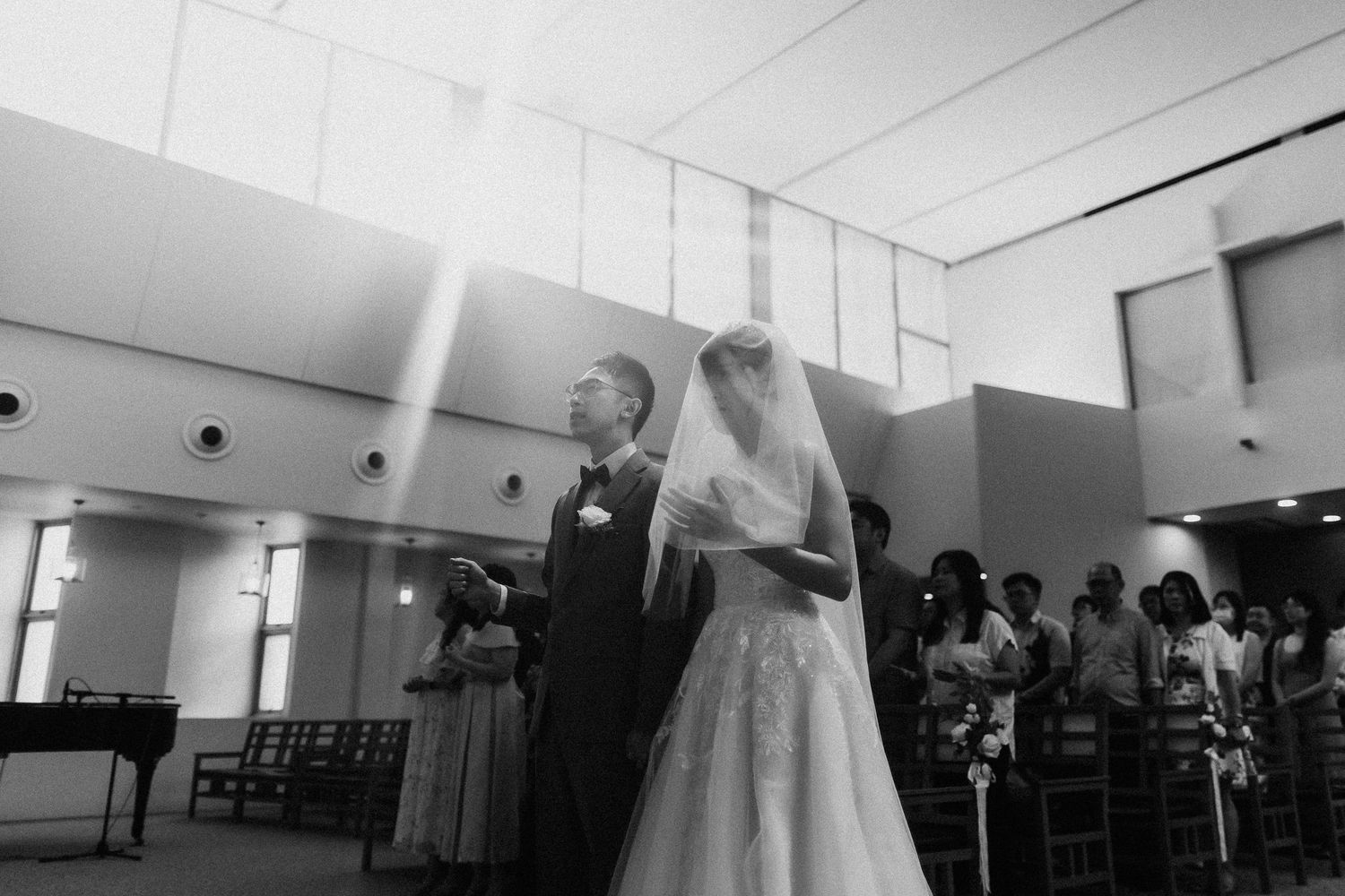 Wedding venue interior with elegant lighting and gathered guests in formal attire.