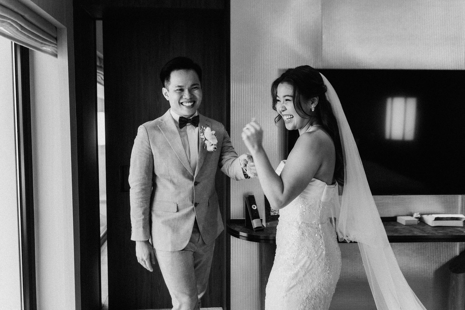 Black and white candid moment showing joyful reactions in a hotel room.