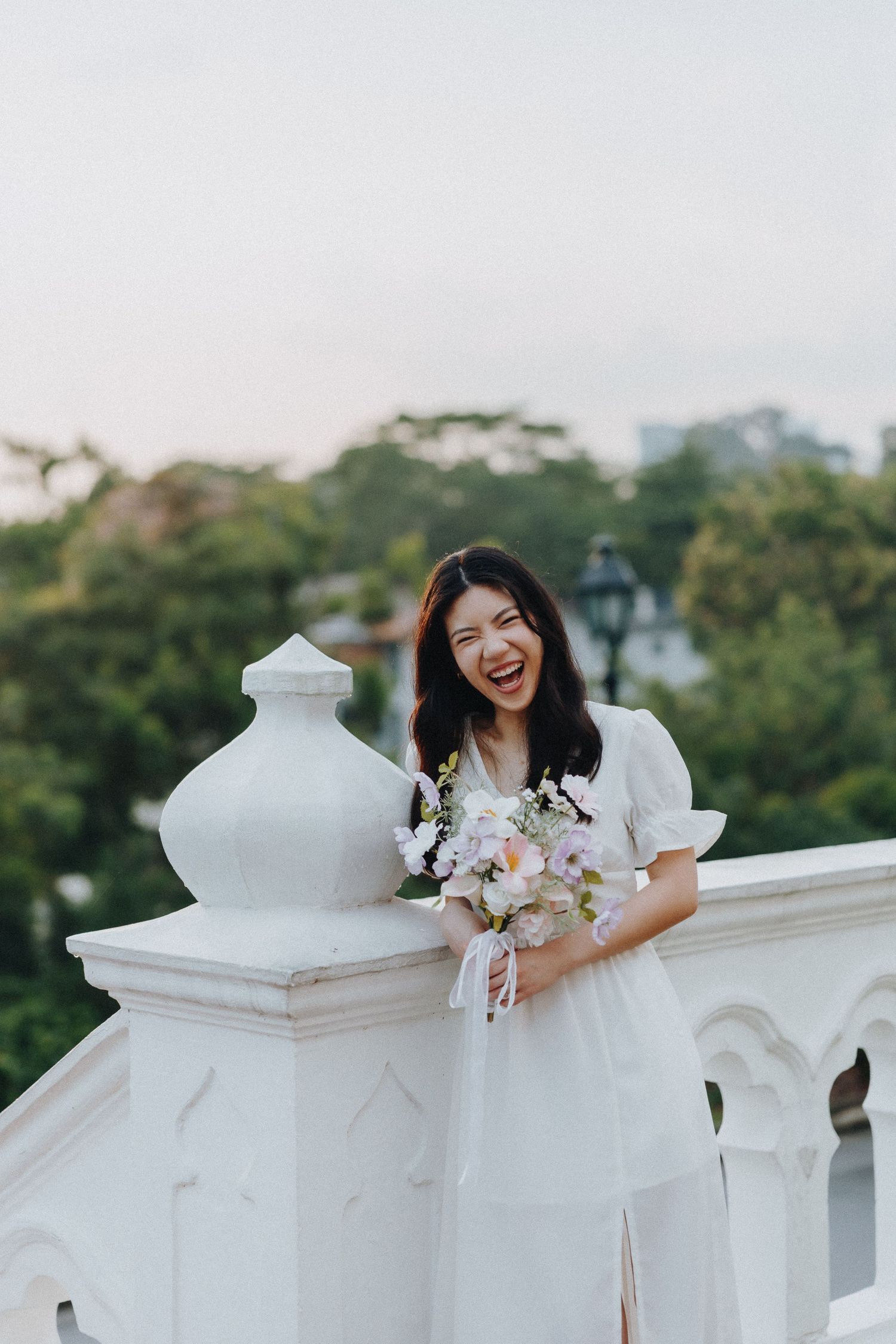 A joyful moment captured at a white balustrade with a delicate bouquet of flowers.