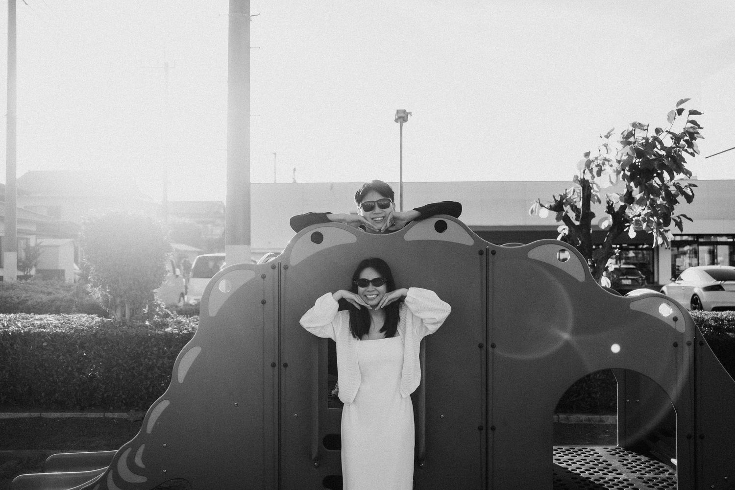 Black and white photo of a couple playing and posing near industrial containers.
