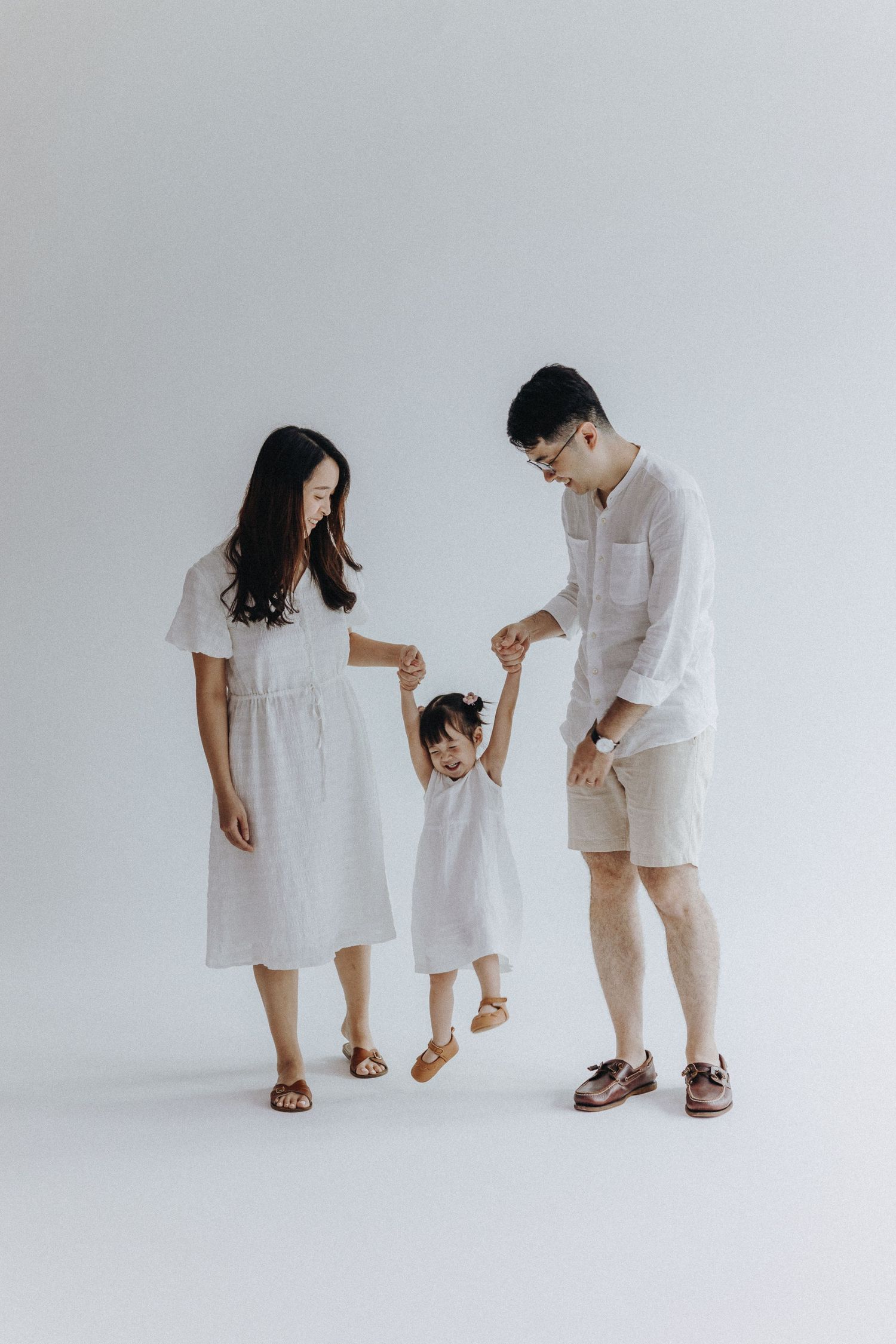 Family walking together in coordinated white outfits against minimalist background.