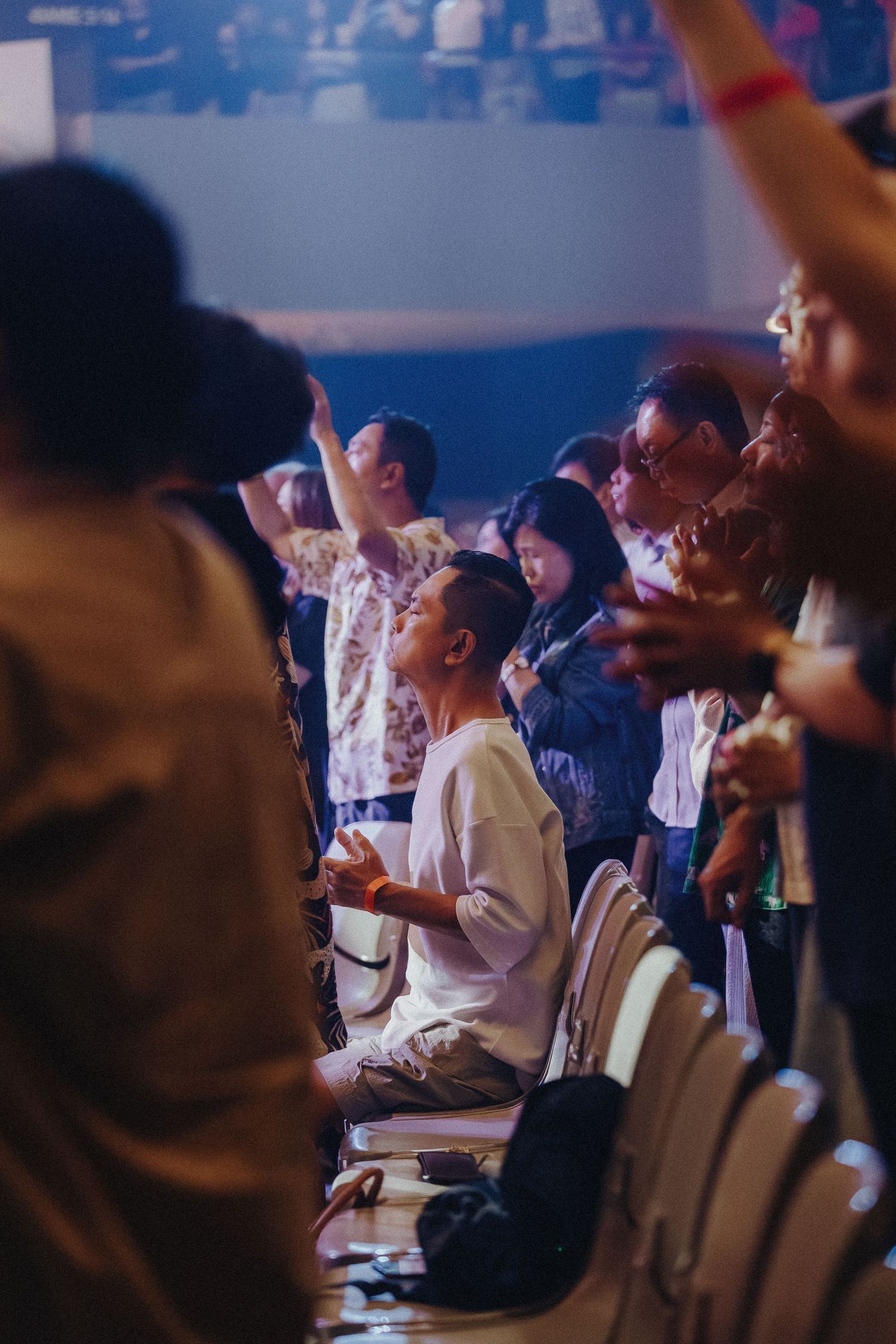 Audience members raise their hands enthusiastically during a live performance event.