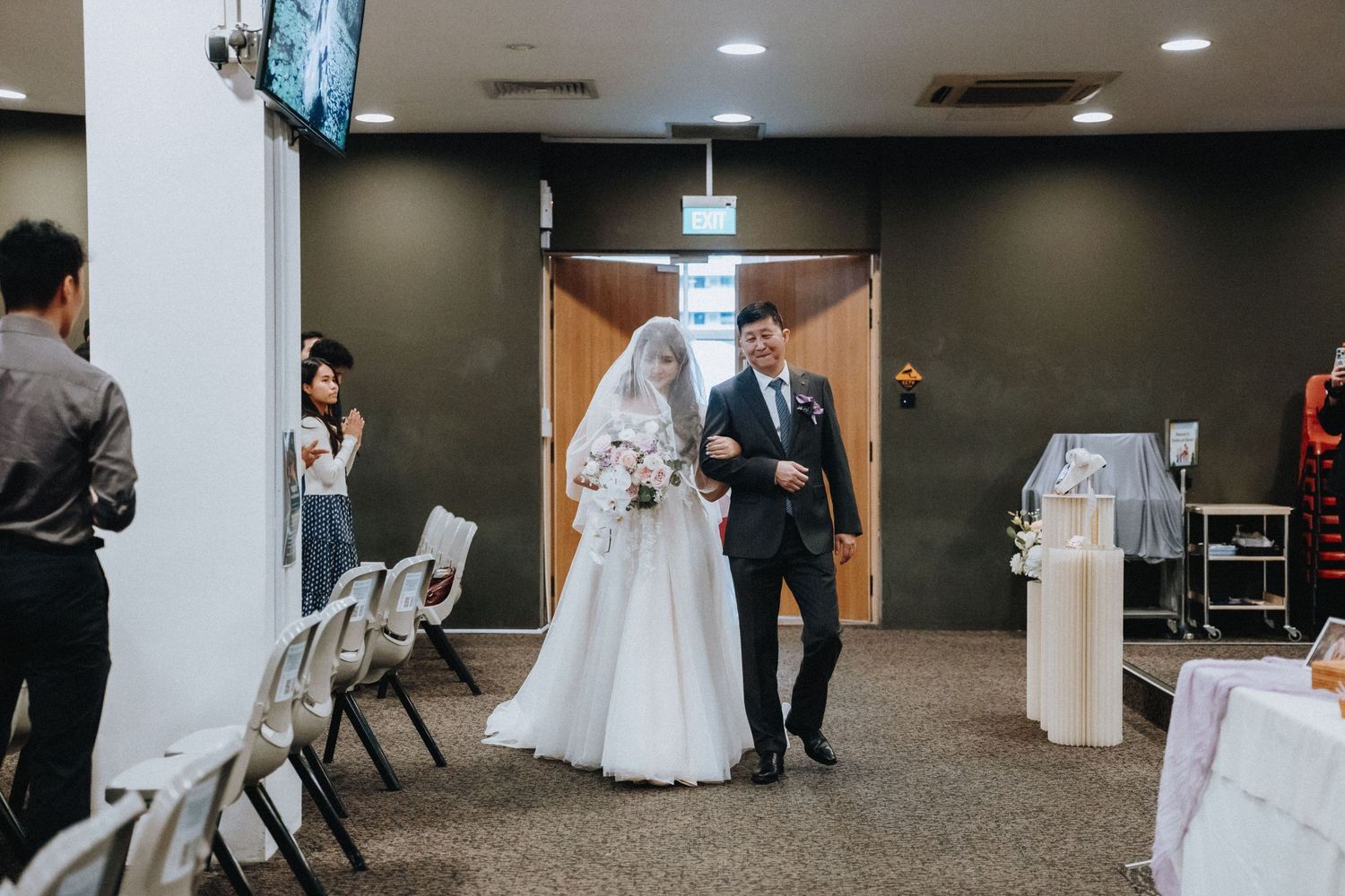 Couple walking down aisle during wedding ceremony in modern indoor venue.