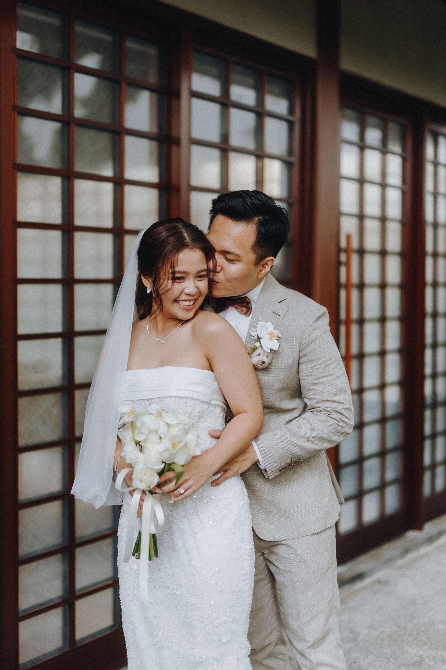 A couple in wedding attire share an intimate moment against traditional Japanese sliding doors.