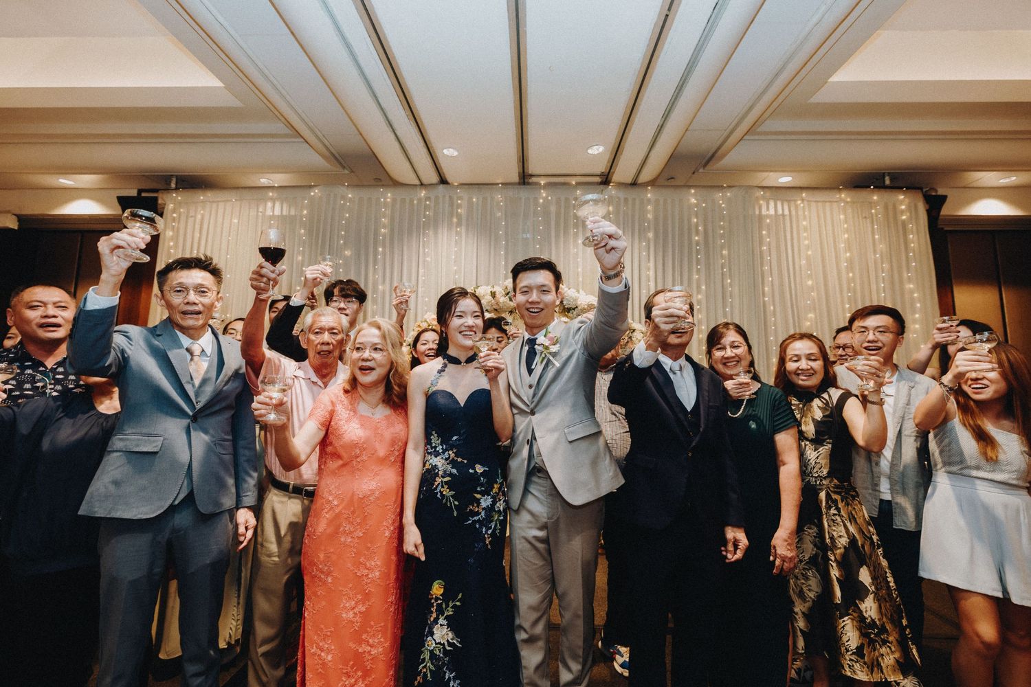 Wedding reception celebration with guests dancing under elegant chandeliers.