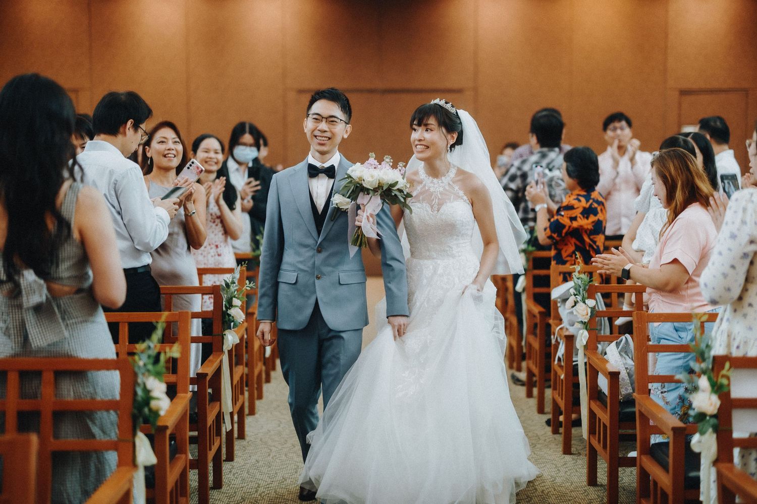Wedding ceremony in progress inside a church with guests seated on wooden pews.
