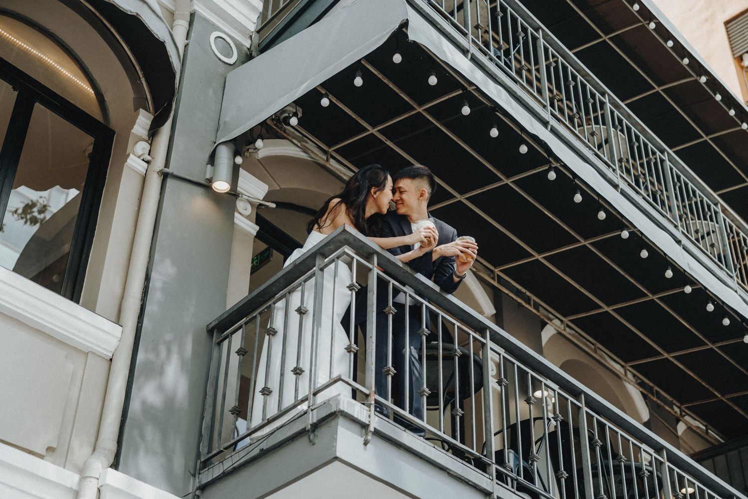 Black metal balcony with ornamental railings against a classic grey building facade.
