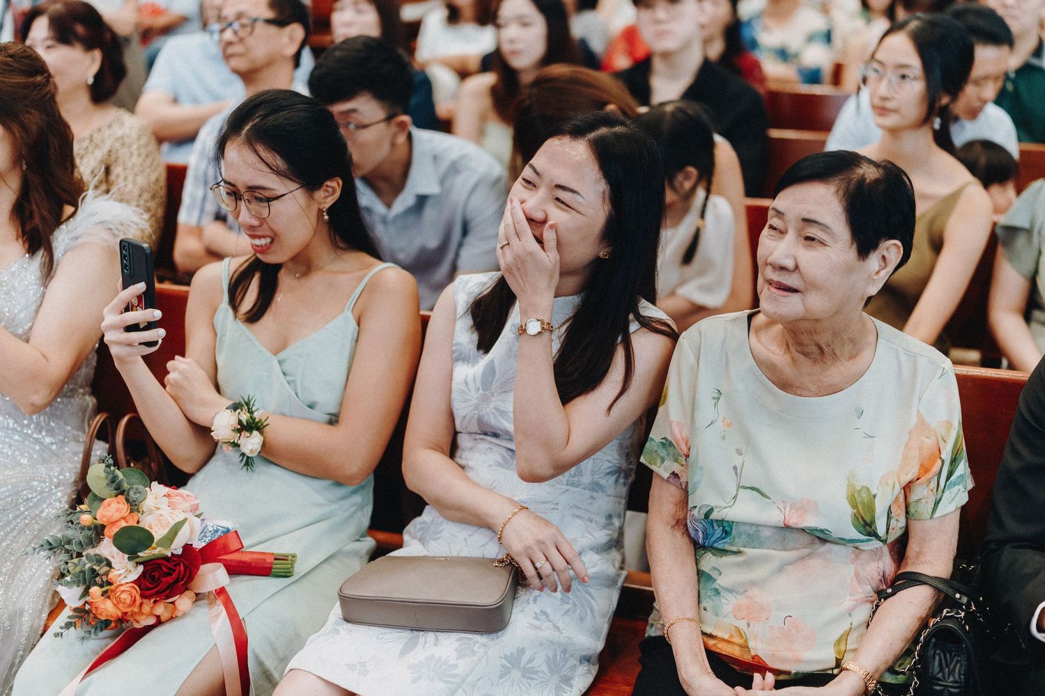 Wedding guests showing emotional reactions during ceremony in church pews.