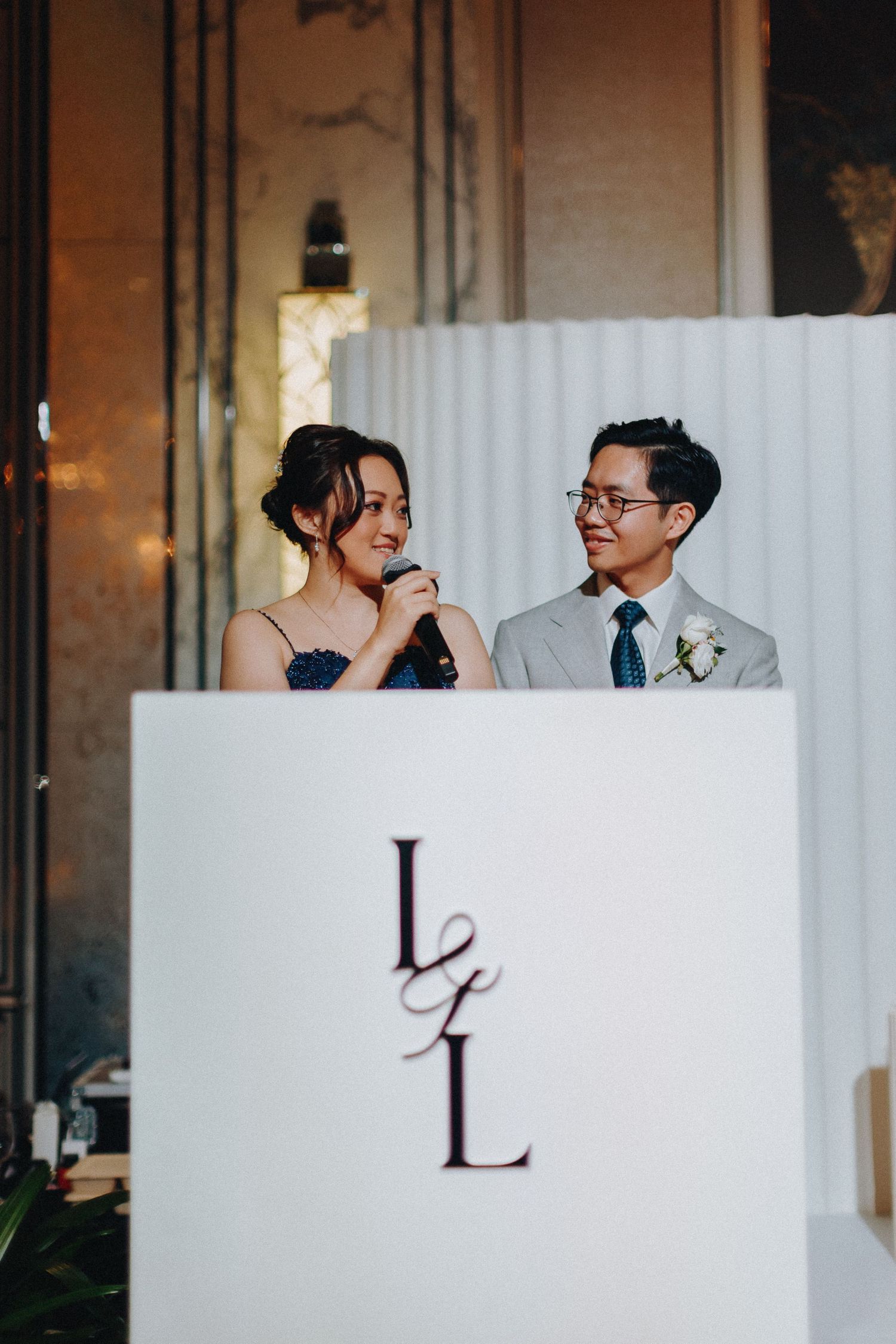 Wedding guests enjoy conversation at a reception behind white panels with black letter decorations.