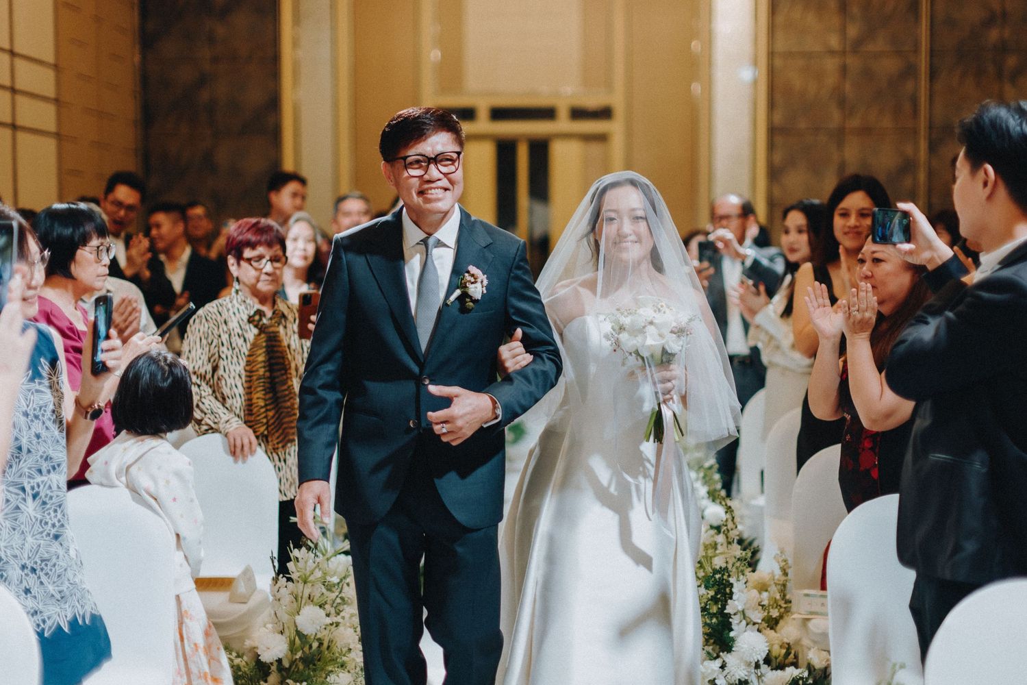 Wedding ceremony in progress with elegant white floral decorations and guests in attendance.