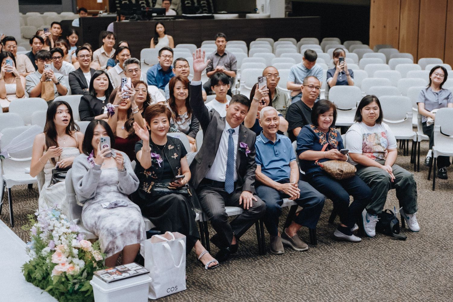 Wide view of wedding ceremony with guests seated in white chairs facing the front.