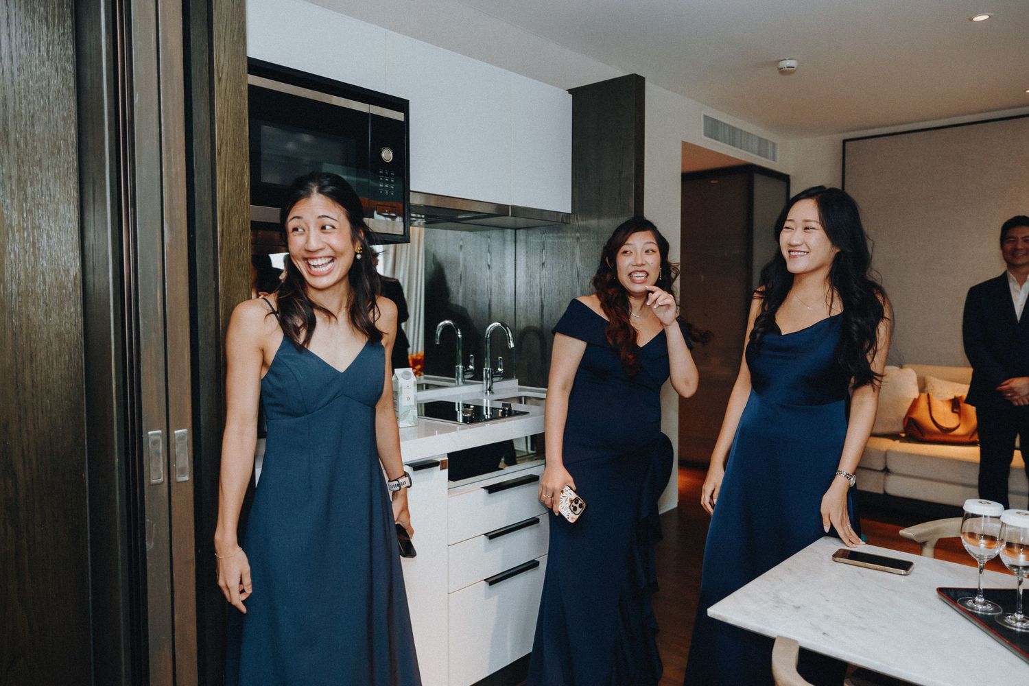 Group wearing navy blue dresses walking together in an elegant indoor venue.