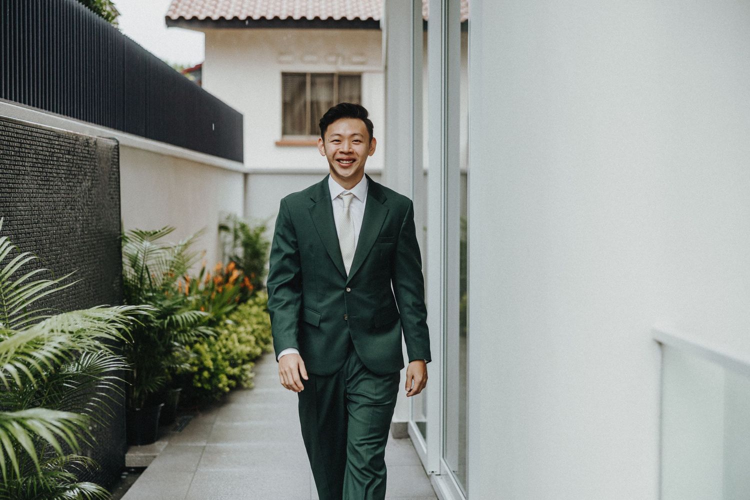 Wedding party candid portrait series showing people in formal attire including a hunter green suit against white walls.
