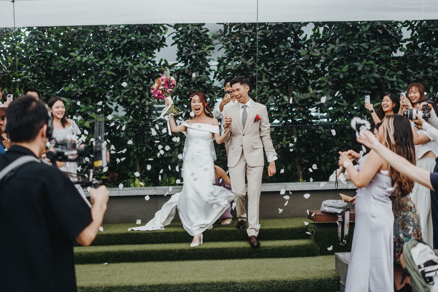 A joyful newlywed couple performs their first dance at an outdoor wedding reception surrounded by guests.