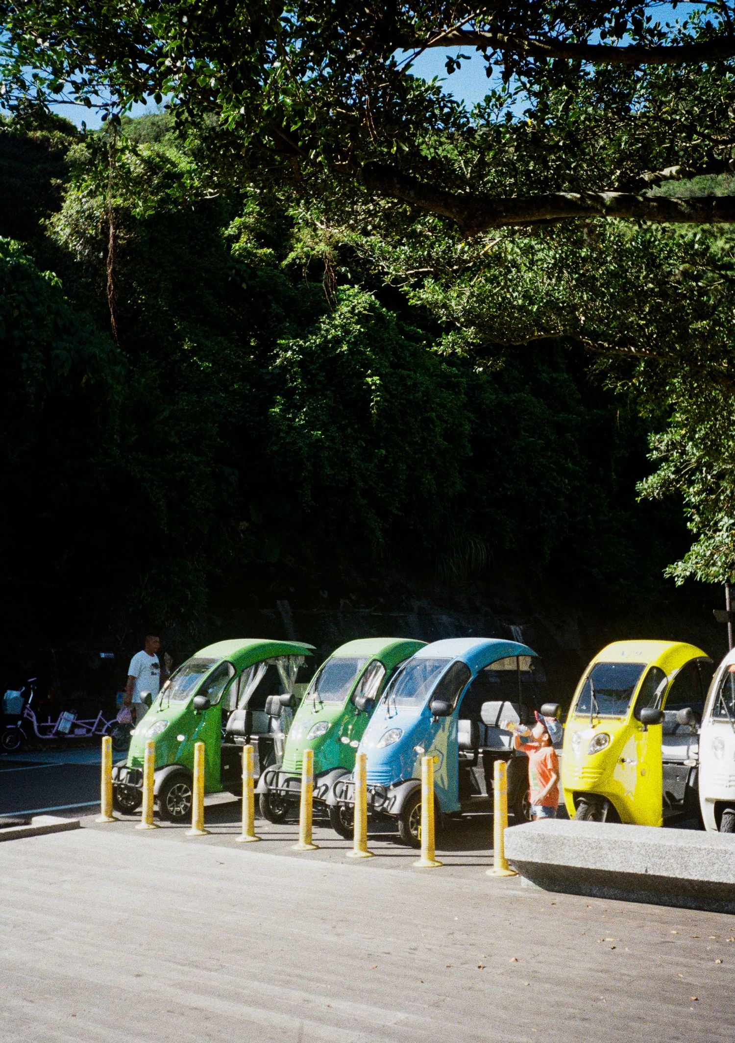 Colorful row of recycling bins arranged in a line outdoors.