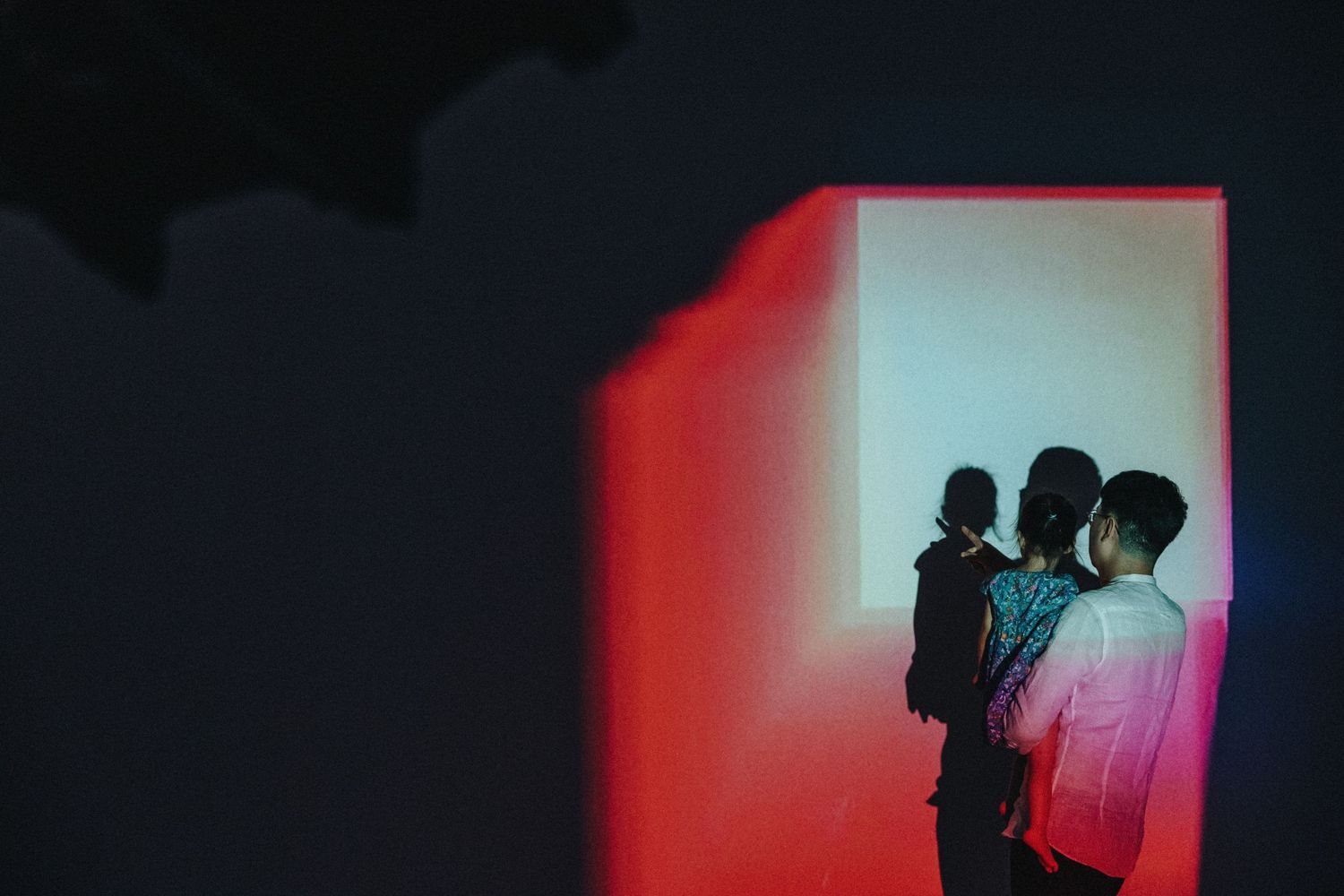 Silhouettes against dramatic red and blue lighting in a dark room.