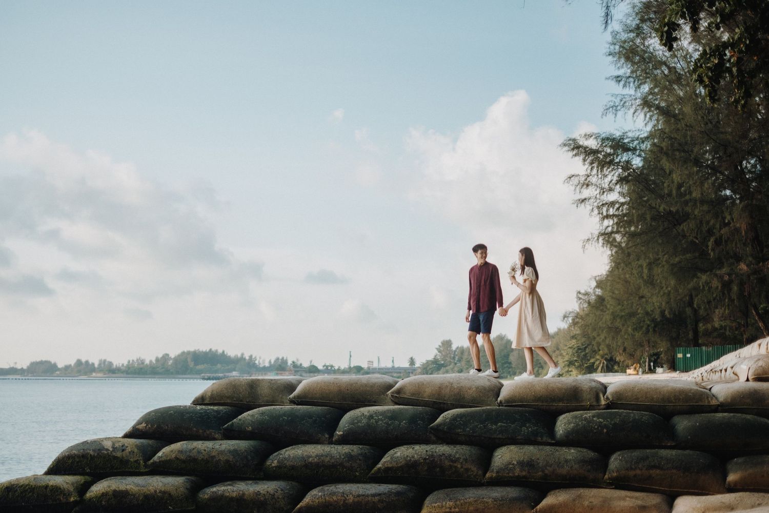 Couple walking along a coastal path with palm trees and ocean views.